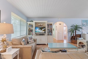 A living room with a sofa, a coffee table, a TV, and a bookshelf.