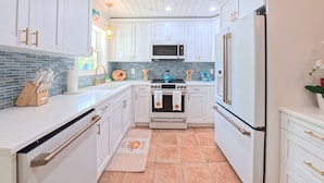 A modern kitchen with white cabinetry, a central island, a microwave, an oven, and a refrigerator. - CASA NEGRONI+DOCK+POOL 🔥❄️PETS+🔥Pit+TiKiBar+ Boat & Parking✅ (Marathon)