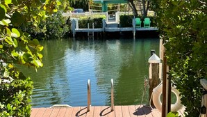 A wooden dock leading to a calm body of water with a house in the background. - CASA NEGRONI+DOCK+POOL 🔥❄️PETS+🔥Pit+TiKiBar+ Boat & Parking✅ (Marathon)