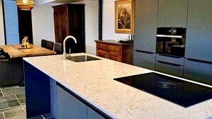 A modern kitchen with a large island, dark cabinetry, and a rustic ceiling. - HVN10 B&B (Stabroek)