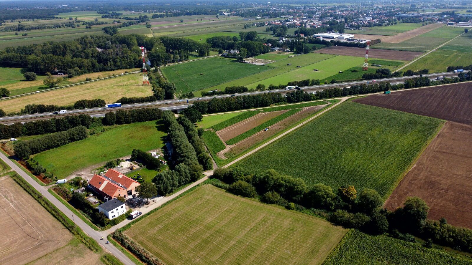 An aerial view of a rural area with fields, a road, and a building with a red roof.