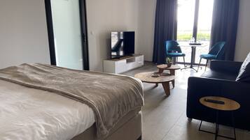 Een moderne hotelkamer met een bed, een televisie, een bank en een kleintje tafeltje.