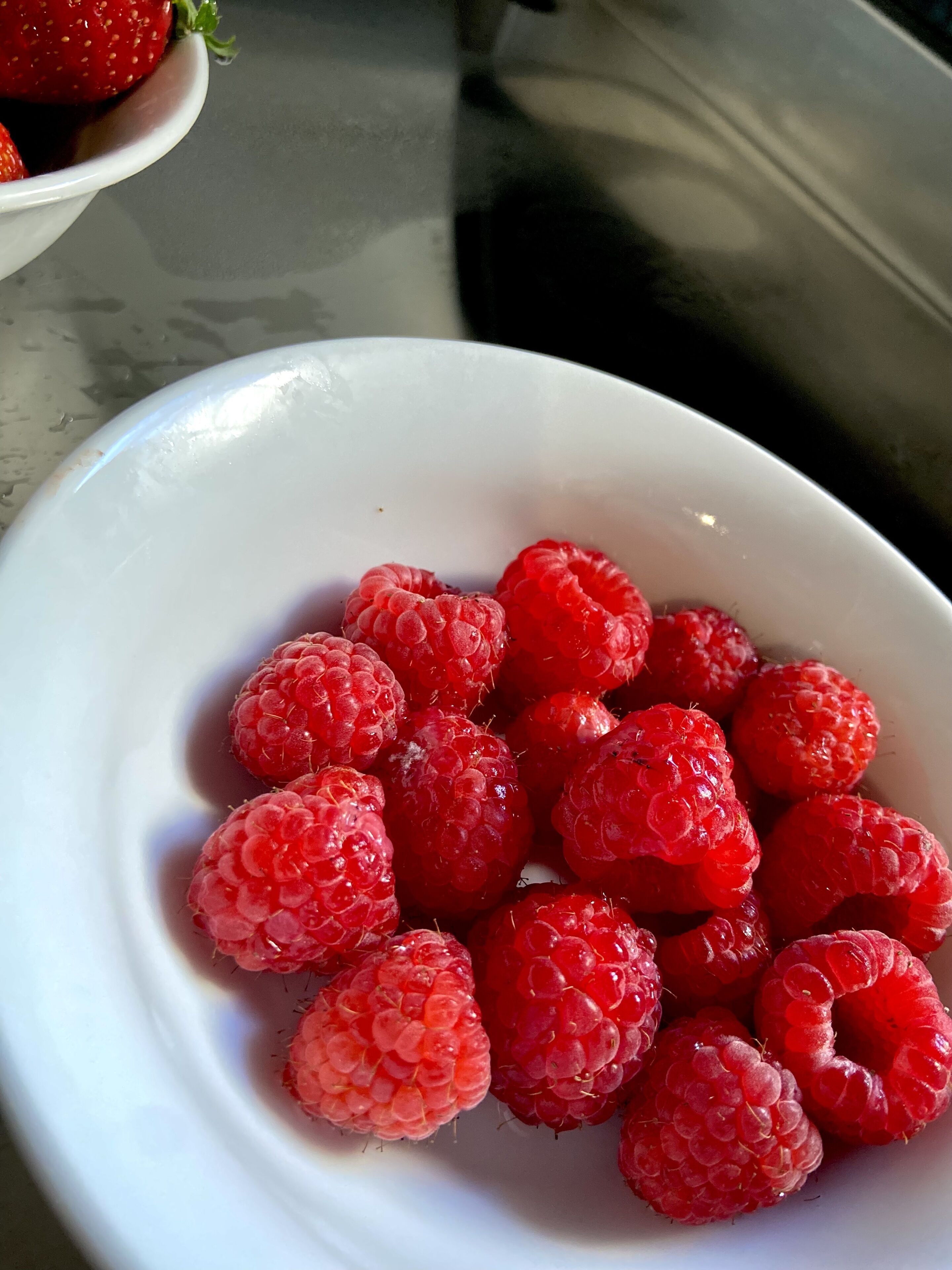 A white bowl filled with fresh raspberries.