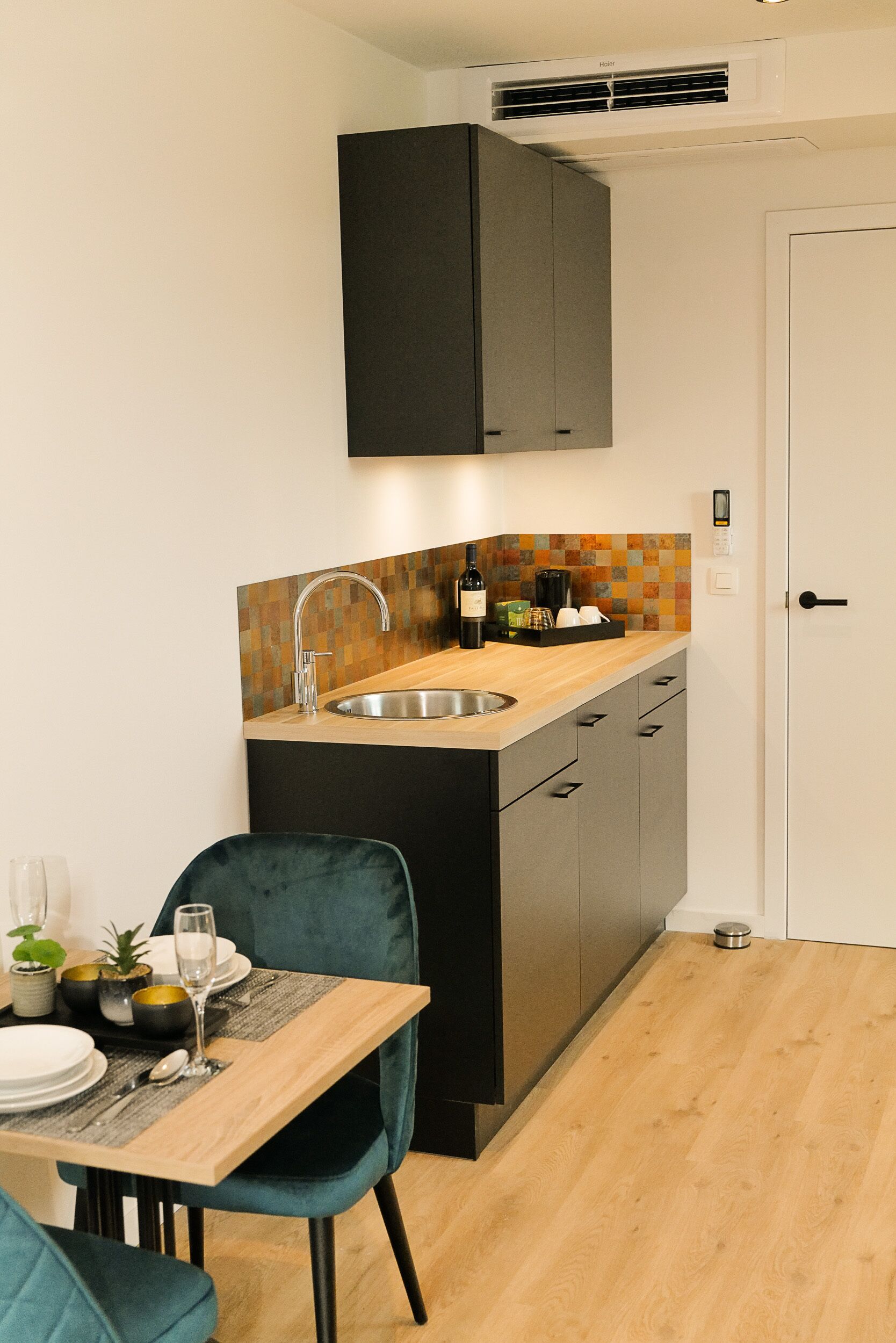 A compact kitchen with a wooden countertop, a stainless steel sink, and black cabinets.