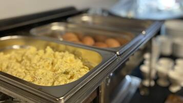 A buffet with various food items including scrambled eggs and meatballs.