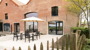 A brick building with outdoor seating and a glass door entrance. - HVN10 B&B (Stabroek)