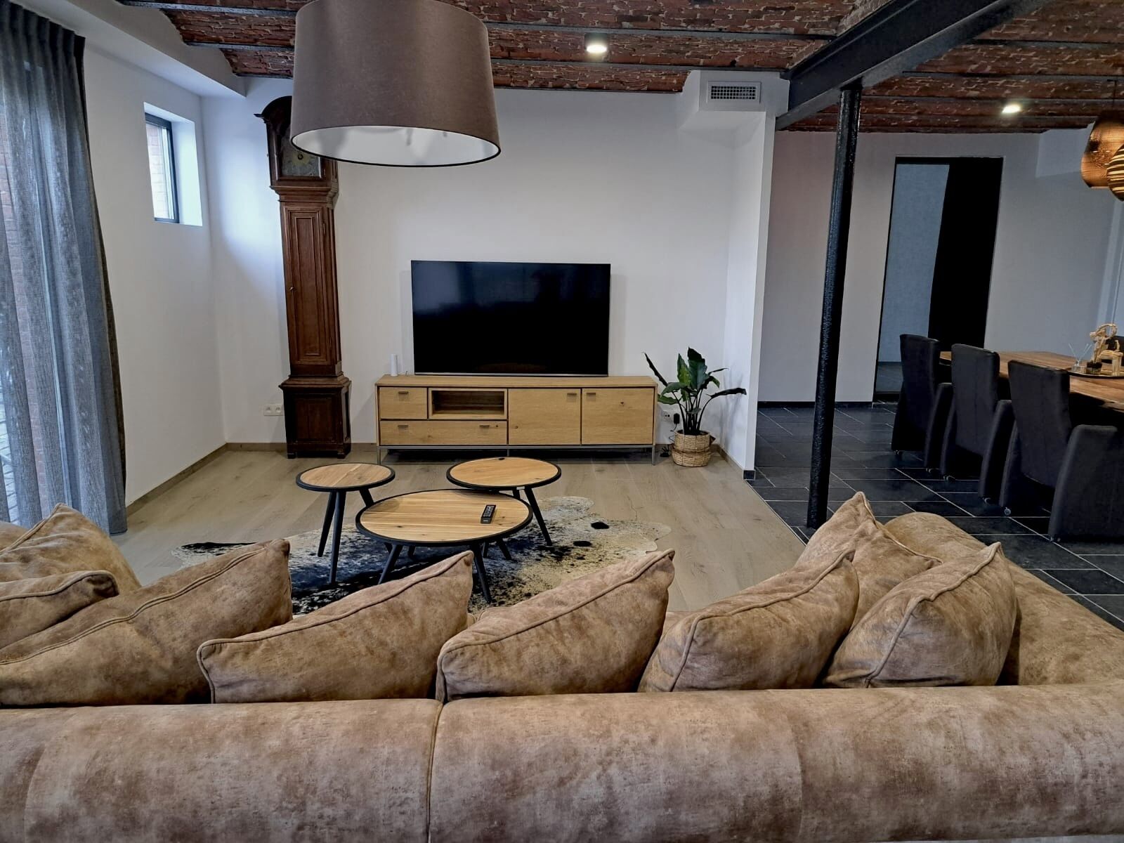 Una sala de estar moderna con sofá, televisión, un mueble de madera y una zona de comedor.
