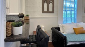 Una habitación pequeña con cama, un escritorio y ventana con persianas.