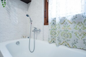 Comfort studio | Badkamer | Een bad/douchecombinatie, een haardroger, een bidet, handdoeken