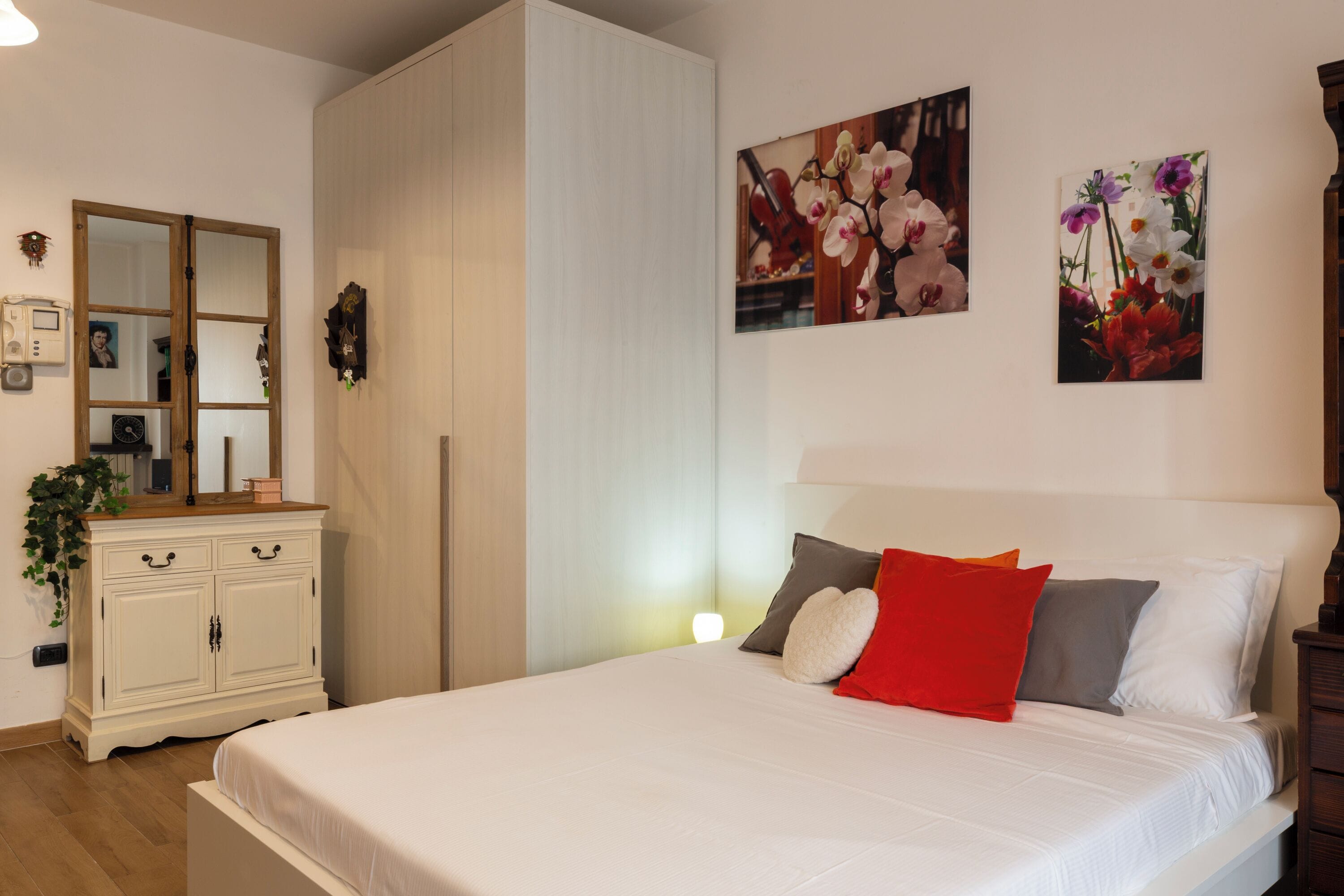 Un dormitorio con una cama, un aparador y dos cuadros colgados en la pared.