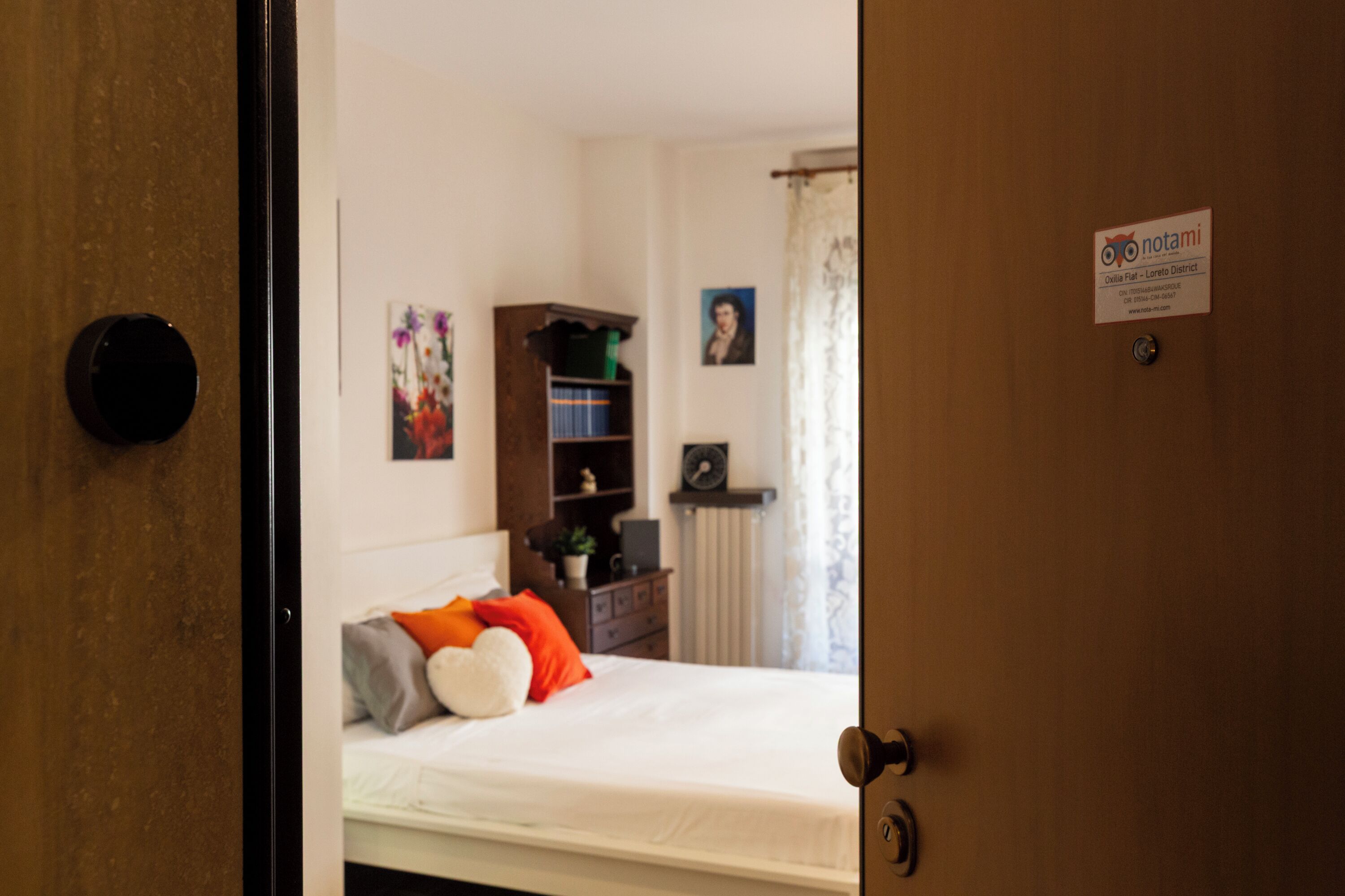 Un dormitorio con cama, cómoda, estantería y una puerta con un letrero.