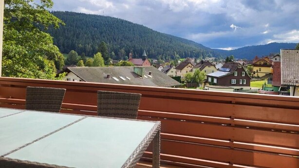 Ein Balkon mit Blick auf ein Dorf und Berge.