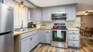 A modern kitchen with grey cabinets, stainless steel appliances, and a wooden countertop. - Cameo Tree Top Chalet - HOT TUB and Pet Friendly (Jasper)