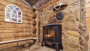 Una cabaña acogedora con pared de piedra, ventana de madera y estufa de leña.
