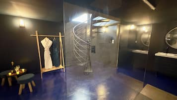 A modern bathroom with a glass partition, a spiral staircase, and a vanity with a mirror.