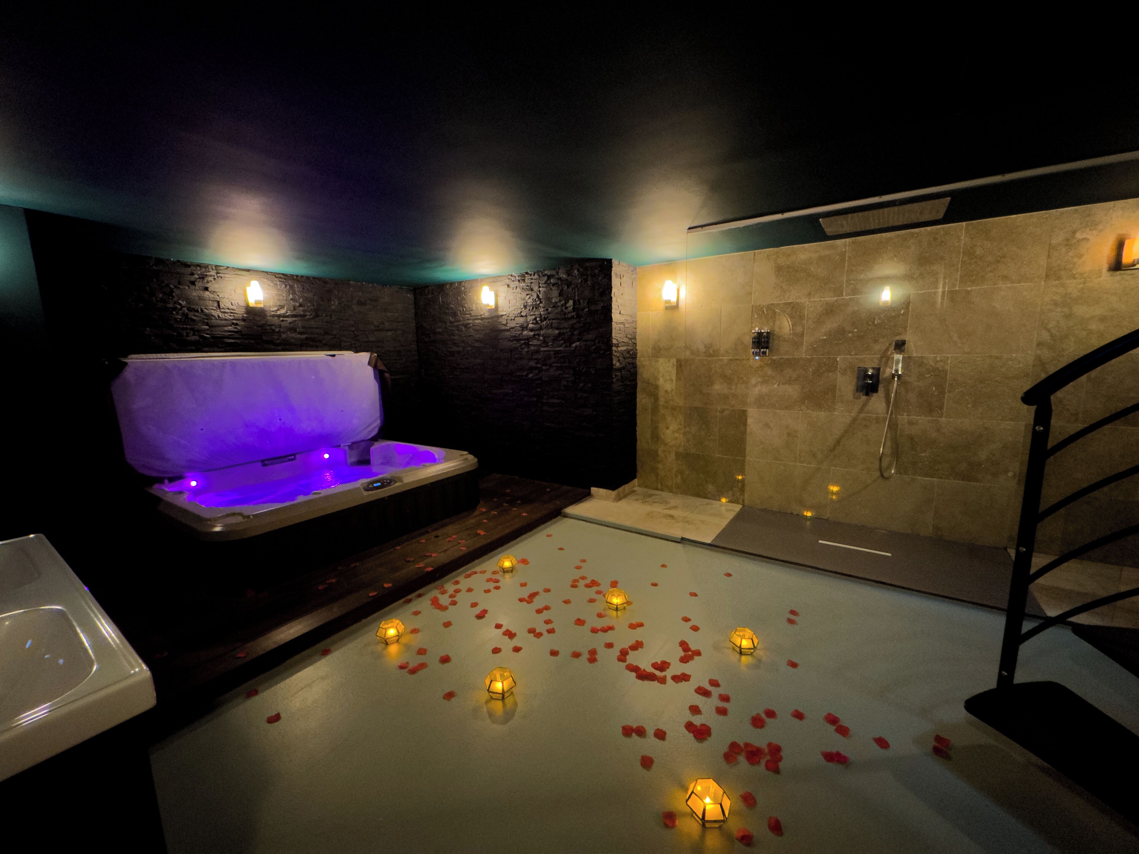 A spa area with a hot tub, a walk-in shower, and rose petals on the floor.