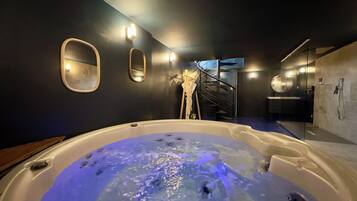 A modern bathroom with a large bathtub, a glass-enclosed shower, and a staircase leading to an upper level.