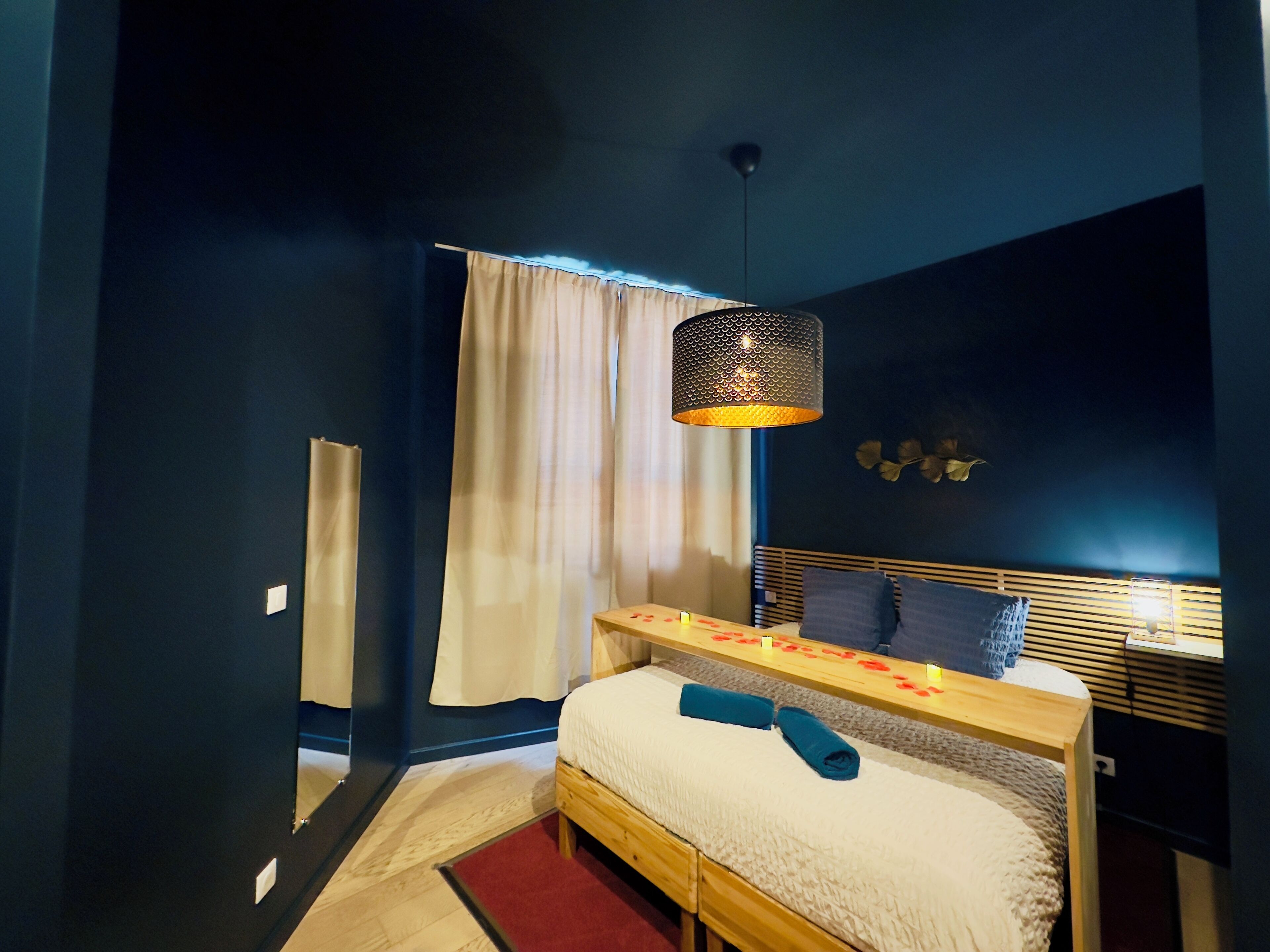 A bedroom with a bed, a bedside table, a lamp, and a window with curtains.