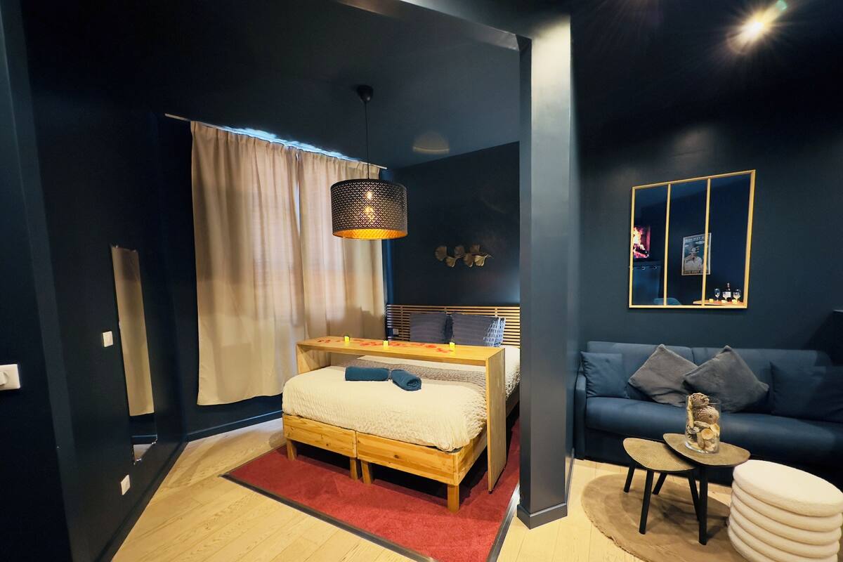A modern bedroom with a wooden bed, a blue sofa, and a small side table.