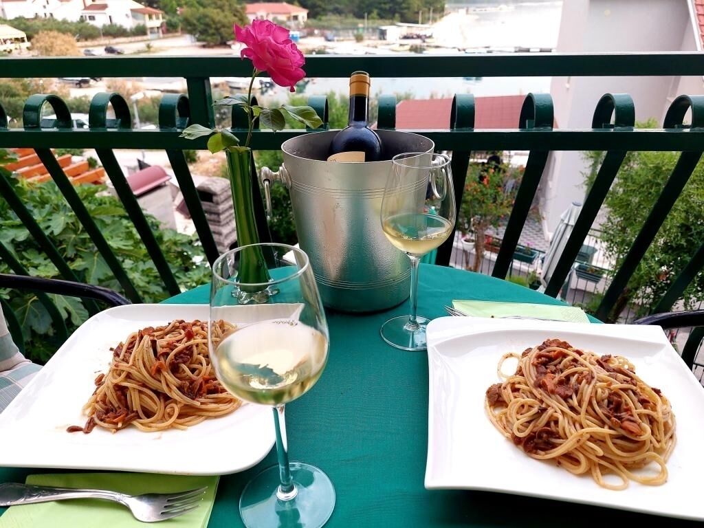 Zwei Teller Spaghetti auf einem Tisch mit einer Weinflasche und einem Weinglas.