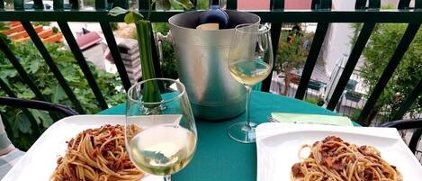 Two plates of spaghetti on a table with a bottle of wine and a glass of wine.