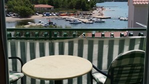 A balcony with a round table and two chairs, overlooking a marina with boats and a beach. - Apartment in Žaborić with Seaview, Balcony, Air condition, WIFI (5177-2) (Šibenik)