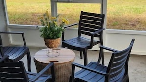 A patio with four chairs and a table, overlooking a pond and greenery.