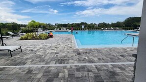 A swimming pool with lounge chairs and a paved deck.