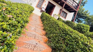 A two-story building with a balcony, a paved pathway, and well-maintained greenery. - Villa Rodriguez Jarabacoa La Vega 3bedroom Hot Jacuzzi (Jarabacoa)