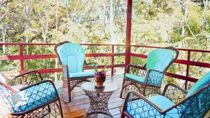 A wooden deck with wicker chairs and a small table, surrounded by a red railing. - Villa Rodriguez Jarabacoa La Vega 3bedroom Hot Jacuzzi (Jarabacoa)