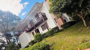 A two-story building with a white facade, a balcony, and a sloped roof. - Villa Rodriguez Jarabacoa La Vega 3bedroom Hot Jacuzzi (Jarabacoa)