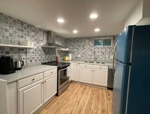 Una cucina con mobili bianchi, un fornello, un lavello e un frigorifero blu.