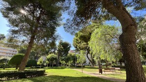 A park with a large tree, a bench, and a clear sky. - FABRA Apartment (Salou)