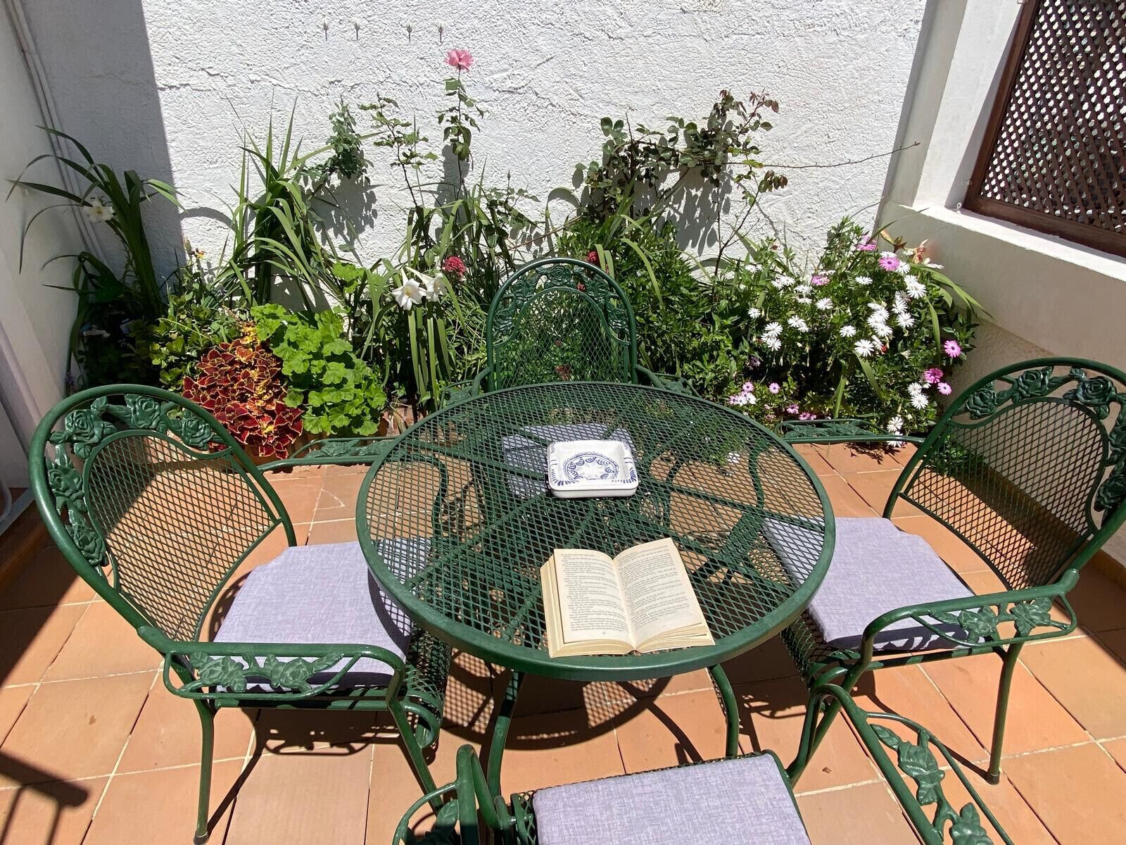 A round metal table with two chairs, an open book, and a cushion on the table.