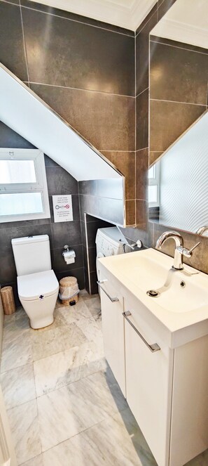 A modern bathroom with a toilet, sink, and a towel rack.