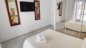 Una habitación de hotel con una cama, un televisor en la pared y obras de arte decorando las paredes.