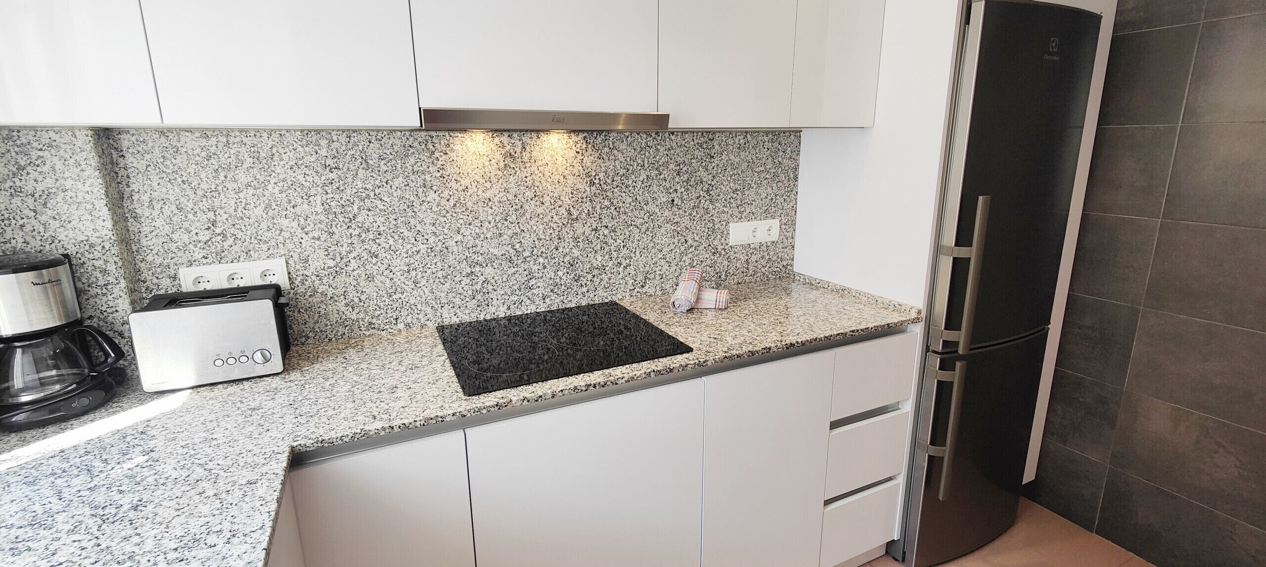A modern kitchen with granite countertops, stainless steel appliances, and white cabinetry.