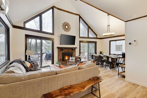 A spacious living room with a large sofa, a wooden bench, a fireplace, and a dining area with a table and chairs.