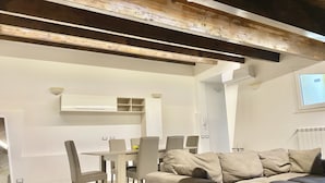 A modern living room with a wooden ceiling, a dining area with a table and chairs, and a large beige sofa. - La Dimora Del Golfo (Gaeta)