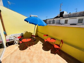 A small outdoor patio with two red tables and chairs, a blue umbrella, and a yellow wall. - La Dimora Del Golfo (Gaeta)
