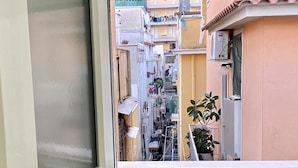 A narrow urban street with closely packed buildings, a visible balcony with a potted plant, and a window frame. - La Dimora Del Golfo (Gaeta)