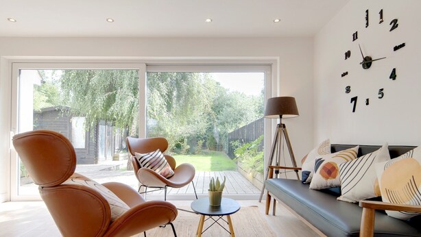 A modern living room with a sofa, two armchairs, a coffee table, and a floor lamp. There is a large window with a view of a backyard. - Pass the Keys | 49 Byron Square Modern and Spacious 3 Bed Home with Free Parking (Cambridge)