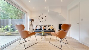 A modern living room with a sofa, two armchairs, a coffee table, and a wall clock. - Pass the Keys | 49 Byron Square Modern and Spacious 3 Bed Home with Free Parking (Cambridge)