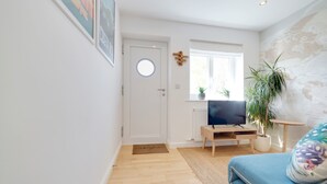 A modern living room with a television, wooden flooring, a blue sofa, and a world map on the wall. - Pass the Keys | Modern & Spacious 1 Bed Terrace with Free Parking (Cambridge)