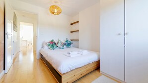 A bedroom with a wooden bed, white bedding, and tropical-themed pillows. - Pass the Keys | Modern & Spacious 1 Bed Terrace with Free Parking (Cambridge)