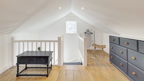 A room with a black table, a dresser, and a small window. - Pass the Keys | 19th Century Barn with Free Parking (Histon)