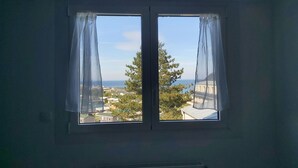 A room with a window overlooking a residential area and a body of water.