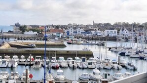 A marina with numerous boats docked, a bridge, and buildings in the background.