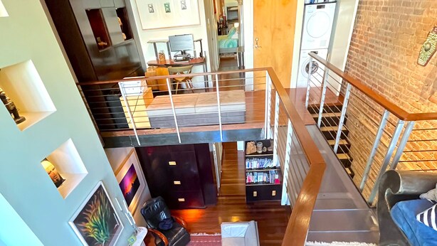 A spacious living area with a high ceiling, a fireplace, a sofa, and a red rug. There is a staircase leading to an upper level. - Modern 2 Bed 2 Bath & Sofa bed w/Dedicated workspace & Large Garden (Brooklyn)
