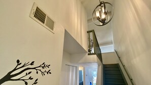 A staircase with a green handrail leading to a landing. A decorative tree decal is on the wall below. - Gorgeous and Bright, Lake Marina, Fish, Golf View! (Branson)
